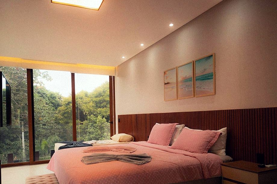 A corner room with a tall window looking into trees